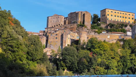 panning shot of pitigliano village with old buildings located on hill during sunny day in tuscany,italy