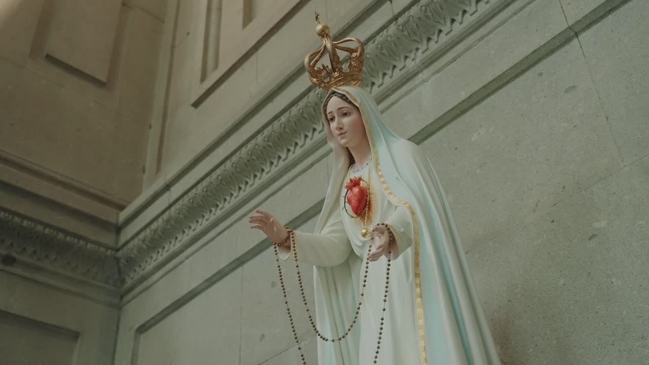 serene marble statue of the Virgin Mary holding a rosary and crowned with gold inside a church