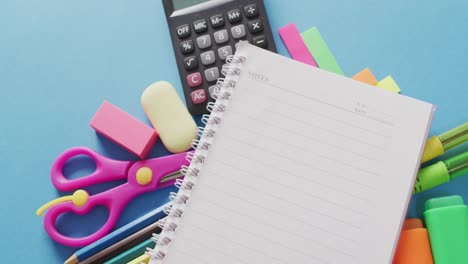 video of school supplies, notebook, pens, marker pen over blue background