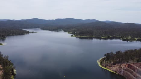 Drone-reversing-over-a-beautiful-lake-with-mountains-in-the-background