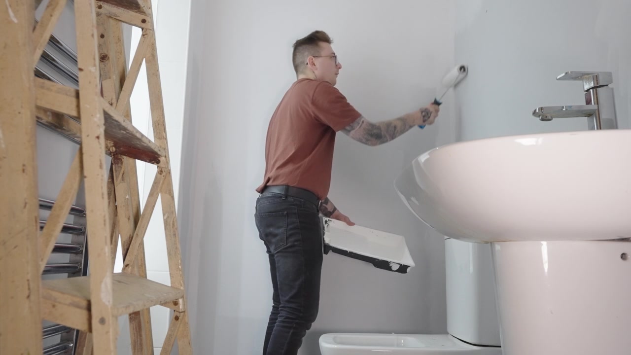 Decoración de reforma de baño, cambio de imagen interior, joven pintando