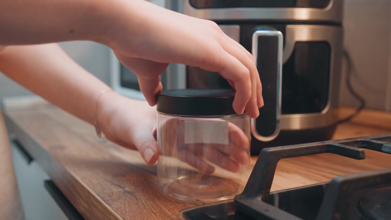 Jar on counter. Container sealed on wooden kitchen counter. Cooking area with closed jar near stove and microwave. Preparing spices in sealed jar on kitchen counter close to cooking appliances