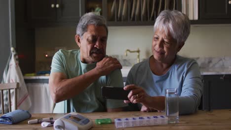 senior mixed race couple having online medical consultation using smartphone