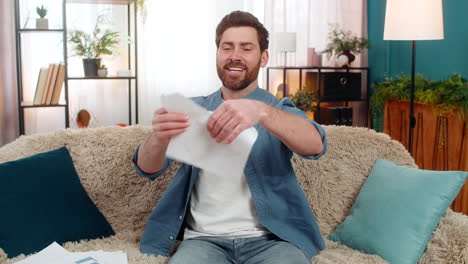 young man happily tears an unnecessary document into pieces feeling relieved and free from concerns