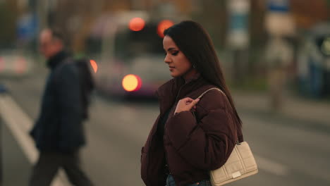 an elegant fashionable woman is crossing the street during dusk in cluj-napoca, romania