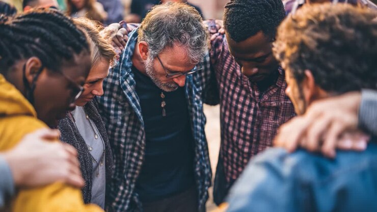 Un gruppo diversificato di persone impegnate nella preghiera, che promuovono l'unità e la connessione spirituale in un'atmosfera di sostegno attraverso momenti condivisi di riflessione e supporto della community durante un vivace raduno