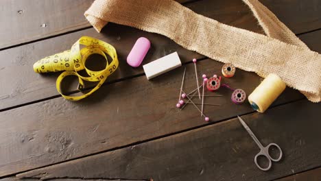 video of measure, scissors, chalk, pins, threads and hessian on wooden background with copy space