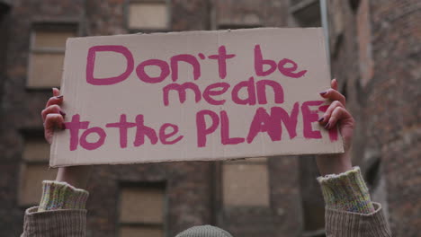 close up view of a cardboard placard with the phase dont be mean the planet holded by a woman during a climate change protest 1