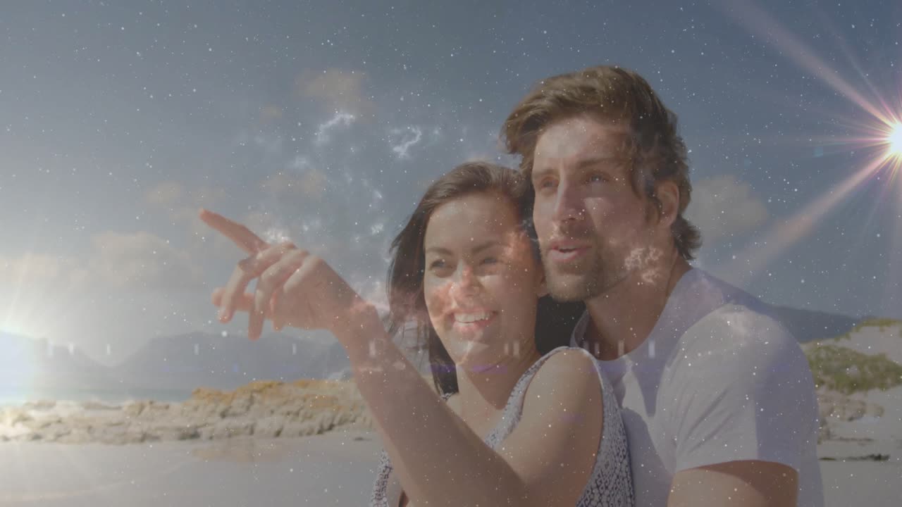 Pareja de pie en la playa admirando la vista, mujer señalando el horizonte, provocando estrellas y un destello que impulsa el turismo.