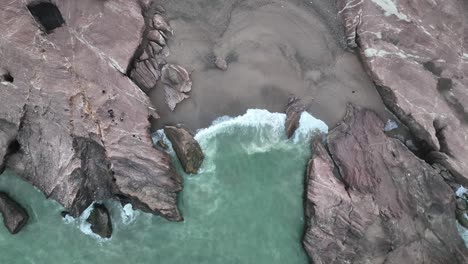 Von-Oben-Nach-Unten-Gerichtetes-Drohnen-Filmvideo-Von-Wellen,-Die-An-Den-Felsen-Am-Strand-Von-Gadani-Beach-In-Pakistan-Brechen