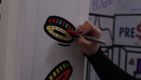 Close-up-shot-of-artist's-hand-making-colorful-drums-with-the-help-of-felt-pen