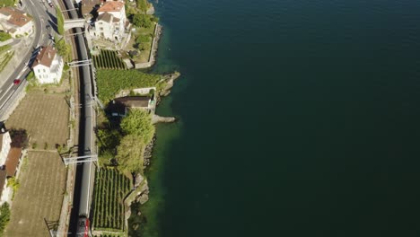 aerial top down view of swiss train passing along the shore of lake léman in lavaux vineyard