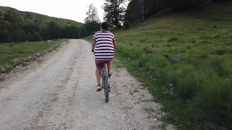 primer plano de un ciclista masculino filmado desde atrás en una carretera rural