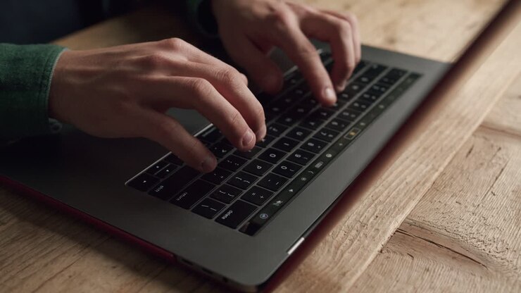 Hand einer nicht erkennbaren Person tippt auf der Laptop-Tastatur