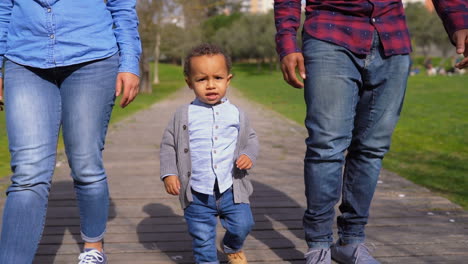 Boy-walking-in-park-with-Afro-american-father,-mixed-race-mother