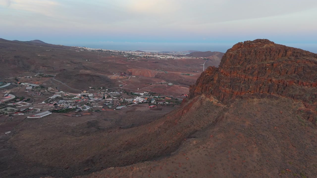 Aerial view of Roque Aguayro geological monument and volcanic landscape in Gran Canaria at dusk with the ocean in the background