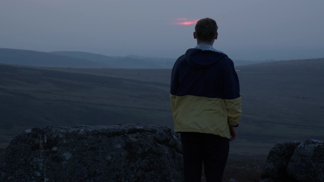 Uomo felice che balla al tramonto nella brughiera di Dartmoor nel South Devon, Inghilterra, Regno Unito. Ripresa al rallentatore.