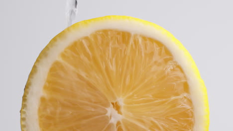 slow motion macro shot of flowing water from lemon slice on white background