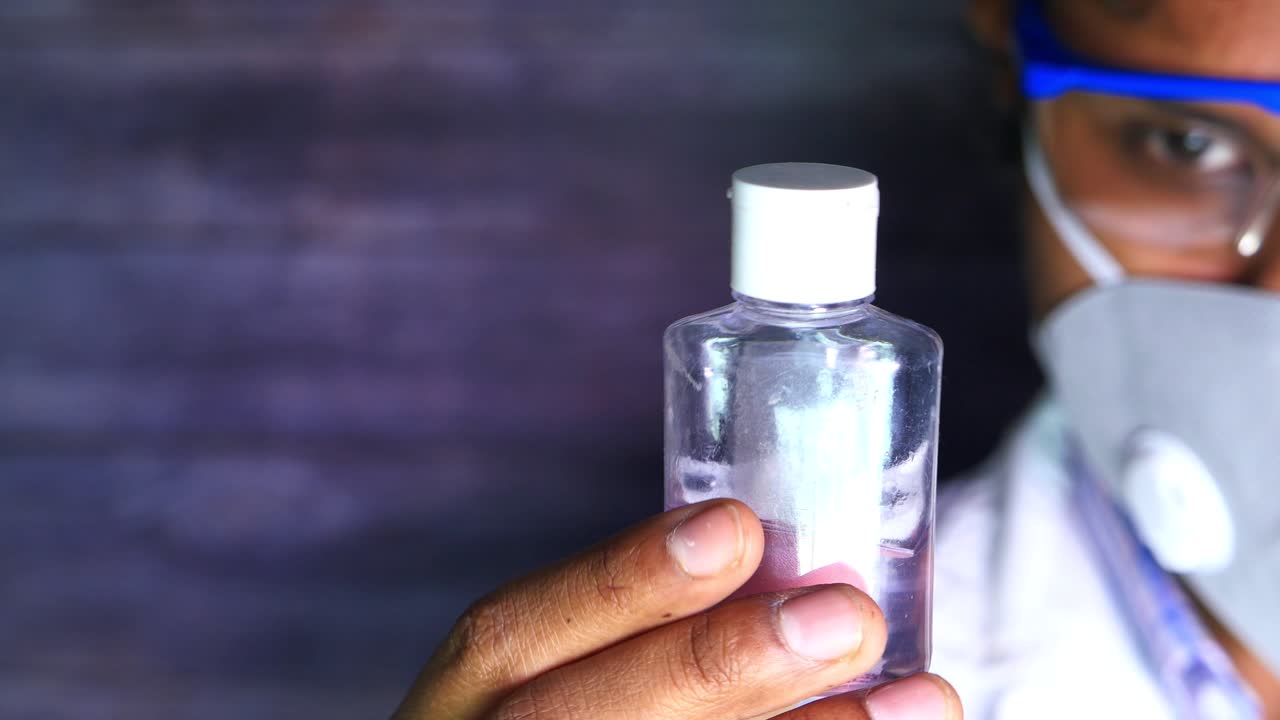 Disinfettante per le mani nelle mani di uno scienziato che indossa una maschera protettiva e occhiali di sicurezza