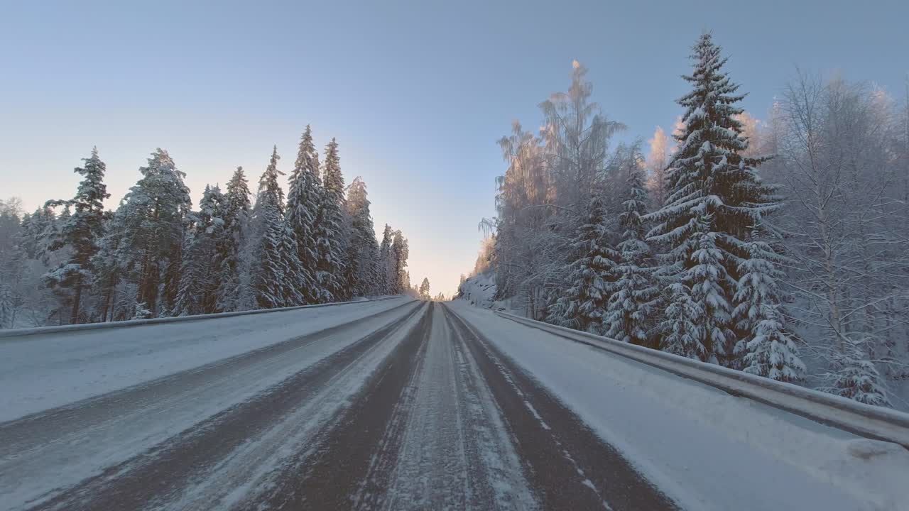 Winter driving POV through scenic forest landscape with dazzling sunlight