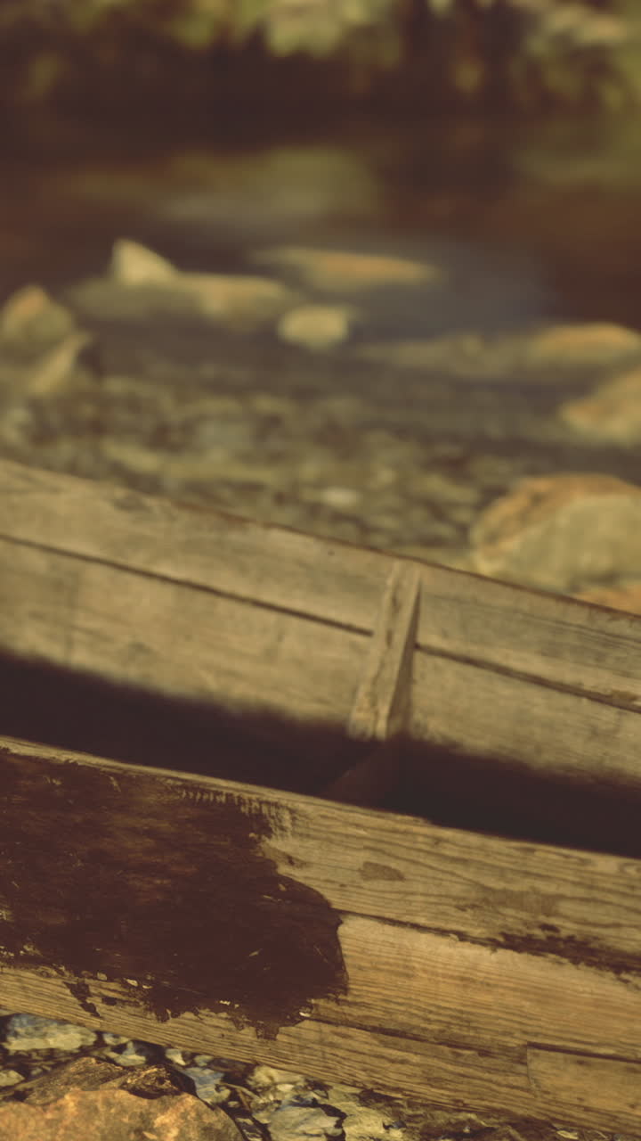 Barca di legno scolorita appoggiata sulla riva del fiume sotto la luce dorata del sole