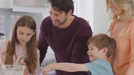 Familie-Mit-Zwei-Kindern-In-Der-Heimischen-Küche-Und-Hat-Spaß-Daran,-Gemeinsam-Kuchen-Zu-Backen