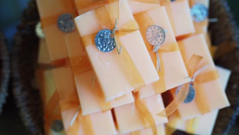 a stack of handmade orange soap bars with decorative ribbons in a brown basket