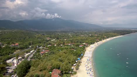 Toma-Aérea-De-Una-Bonita-Playa-Desde-Arriba-Y-Junto-Al-Monte-Olimpo,-La-Montaña-De-Los-Dioses