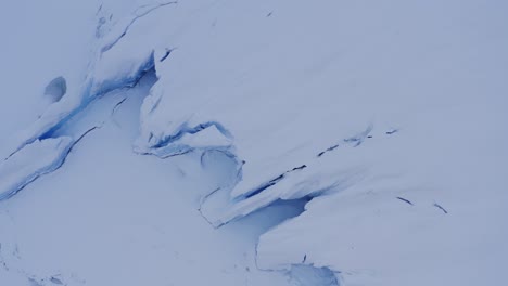 aerial of glacier ice covered in white snow in alaska looking like frozen waves