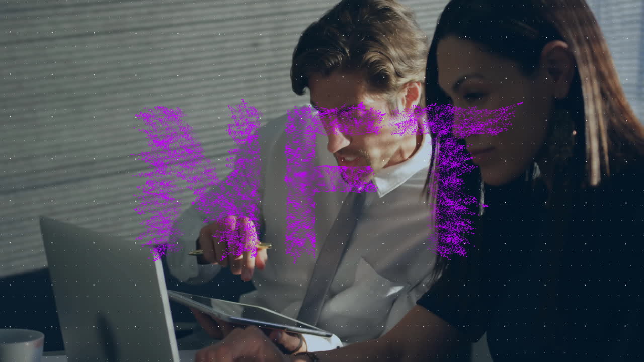 Colleagues working in business office, pointing with pen at laptop and tablet with floating charts