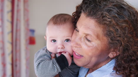 grandmother cuddling baby grandson at home