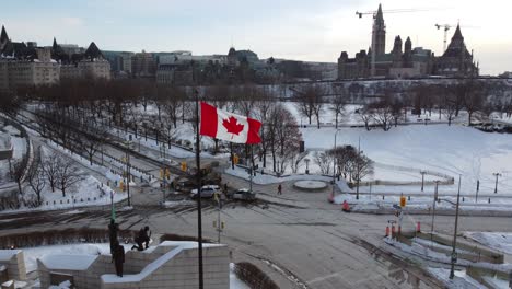 Canadian-flag-in-front-of-excavator-due-to-protests-against-government-measures-taken-by-police,-Canadian-flag-in-foreground---Ottawa,-Ontario