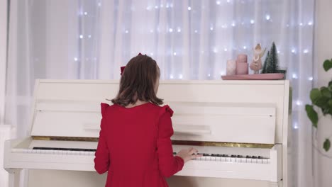 talented young girl in red dress plays white piano