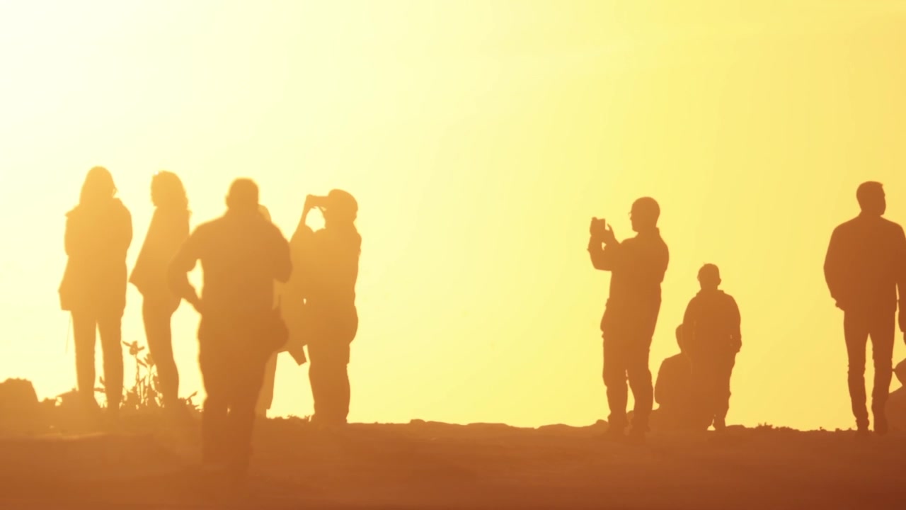 Silhouettes of people in the light of sunset people taking photo on setting sun