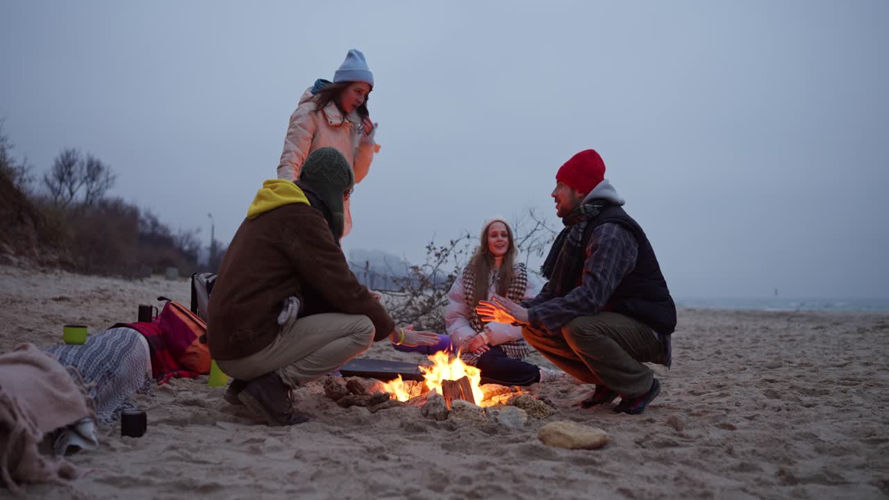 Friends enjoying a campfire on a beach in winter