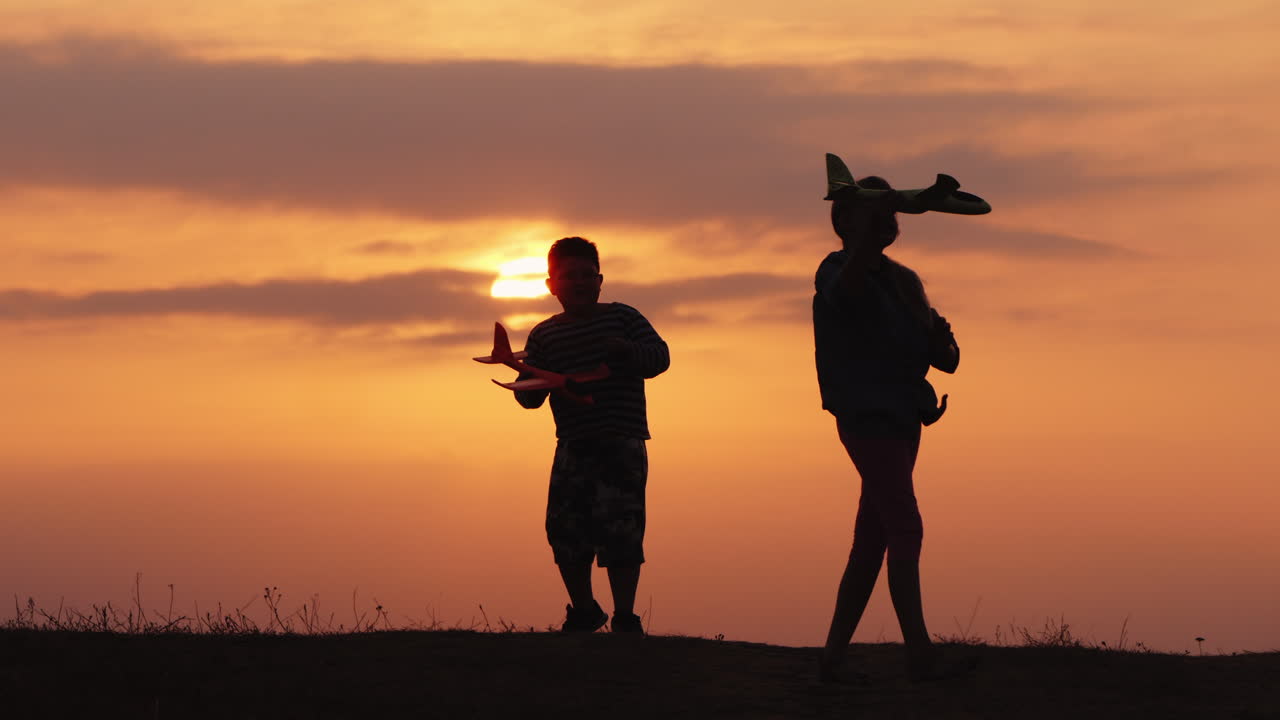 Silhouettes Of A Girl And A Boy Playing Together With Airplanes At Sunset A Happy And Carefree Child