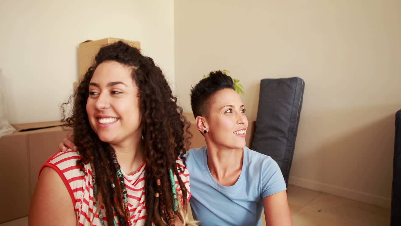 una pareja de lesbianas sonrientes mostrando nuevas llaves.