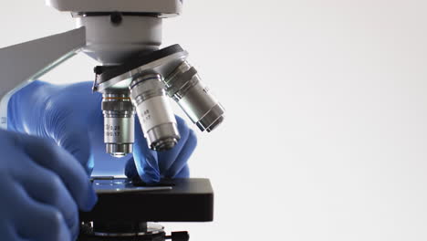 video of close up of scientist using laboratory microscope with copy space on white background