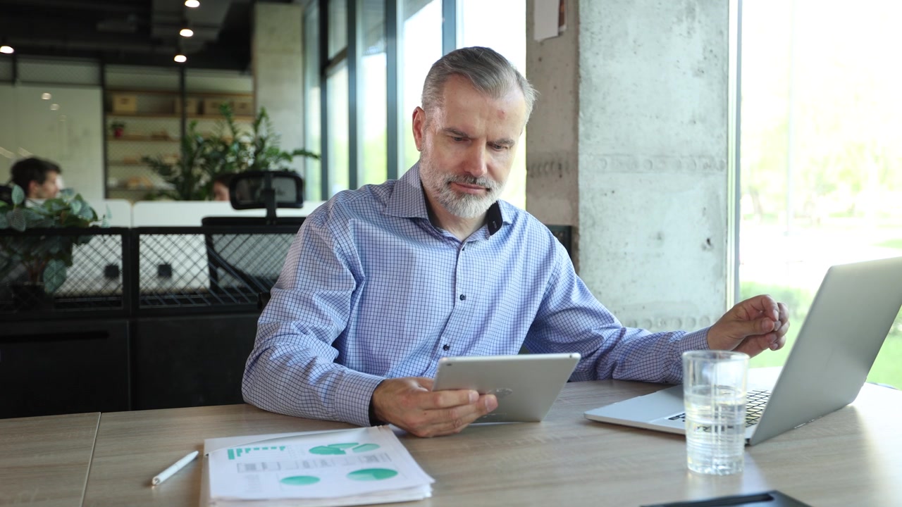 Empresário Focado Trabalhando com Tablet e Notebook em Escritório Moderno