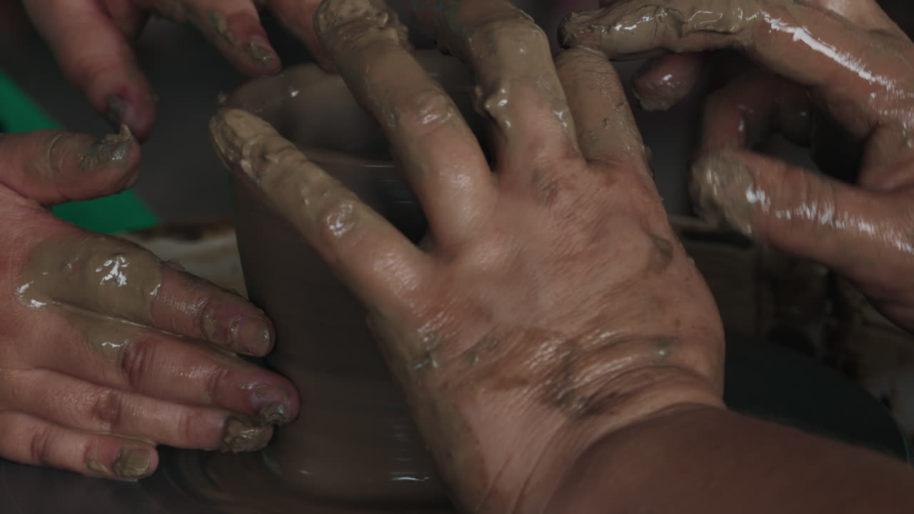 Hands shaping clay on a pottery wheel
