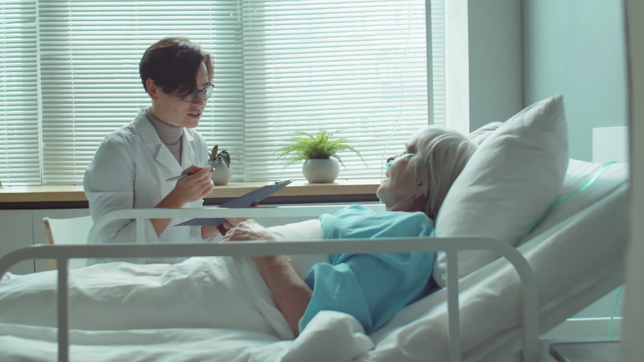 Female Doctor Visiting Senior Woman in Hospital Ward