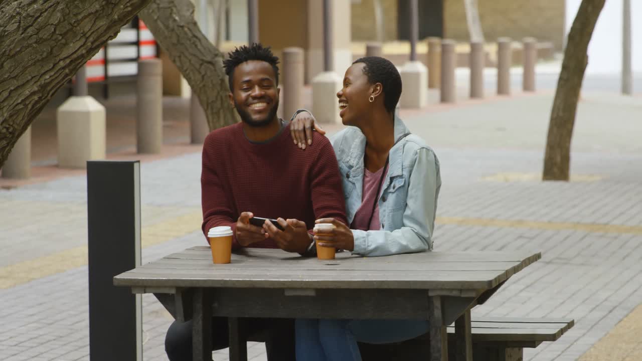 Couple using mobile phone in outdoor cafe 4k