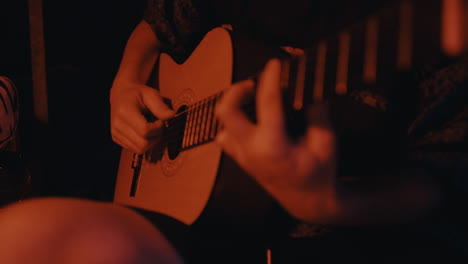 person playing acoustic guitar in red light