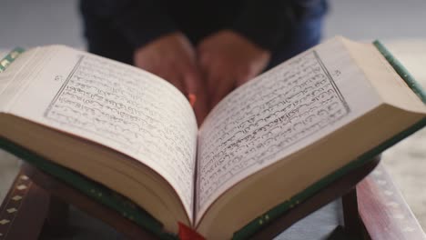 close up of open copy of the quran on stand at home with woman sitting behind 1