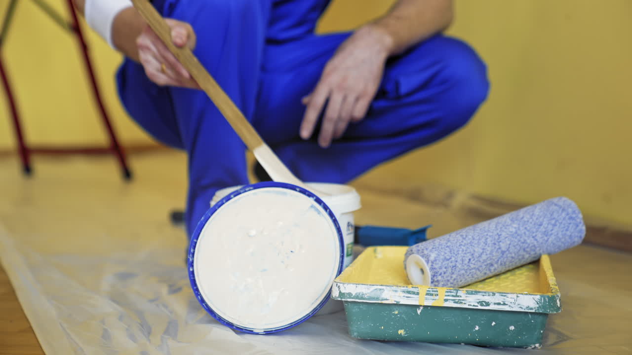 Building tools and paint for room makeover. Worker preparing color before painting walls indoors. Paint tray, white dye in a bucket. Close-up.