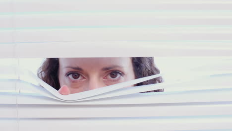 una mujer mirando a través de las persianas.