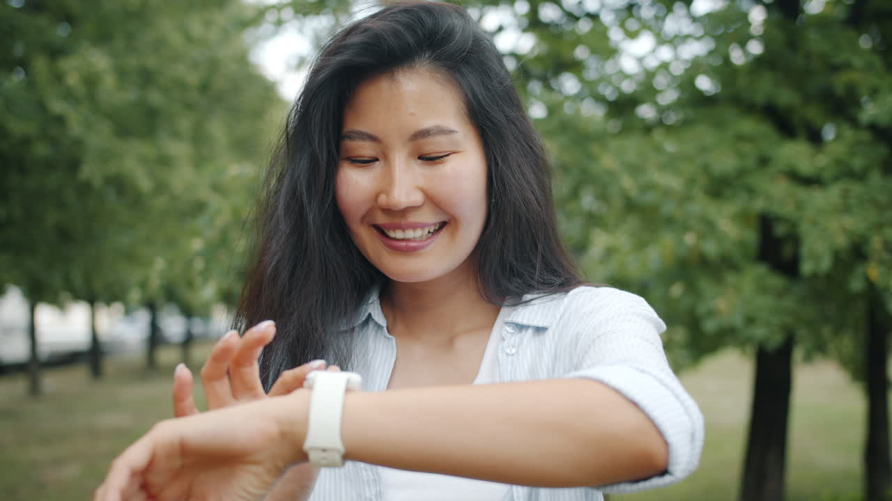 Asian Woman Checking Smartwatch in a Park