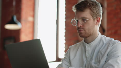 freelancer is working with laptop in cafe closeup portrait of concentrated face of attractive man with glasses