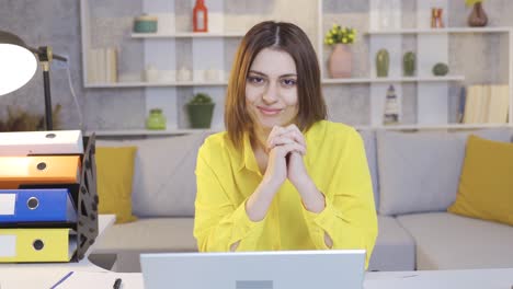 Happy-and-confident-young-entrepreneur-businesswoman-working-from-home-at-computer-looking-at-camera-and-smiling.