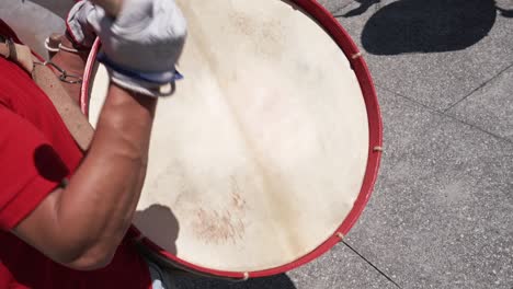 Close up of a percussionist striking a large red drum with a mallet during a folk festival